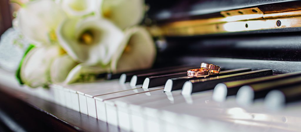 Wedding rings and a bouquet of white callas on the piano keys.