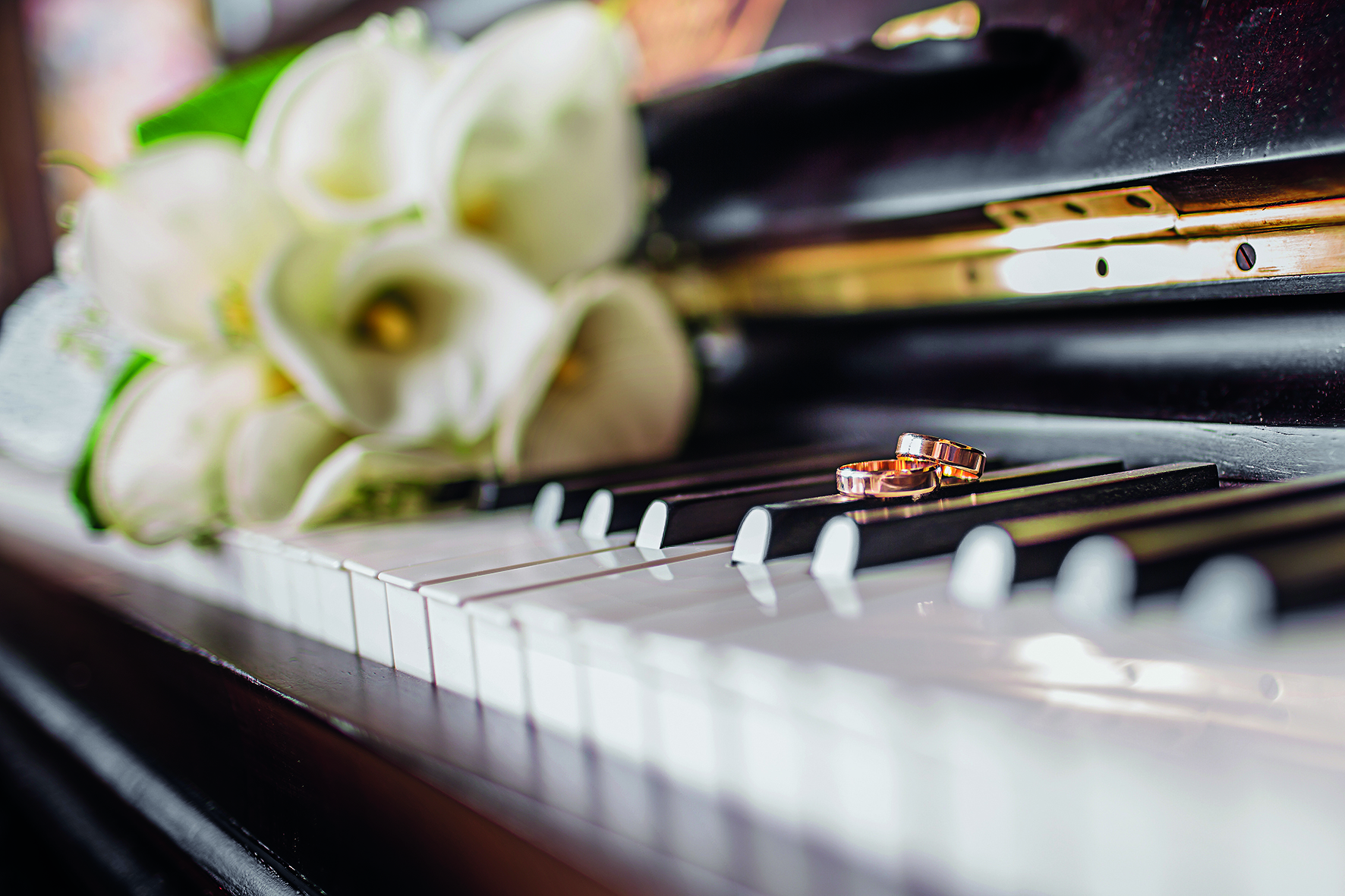Wedding rings and a bouquet of white callas on the piano keys.